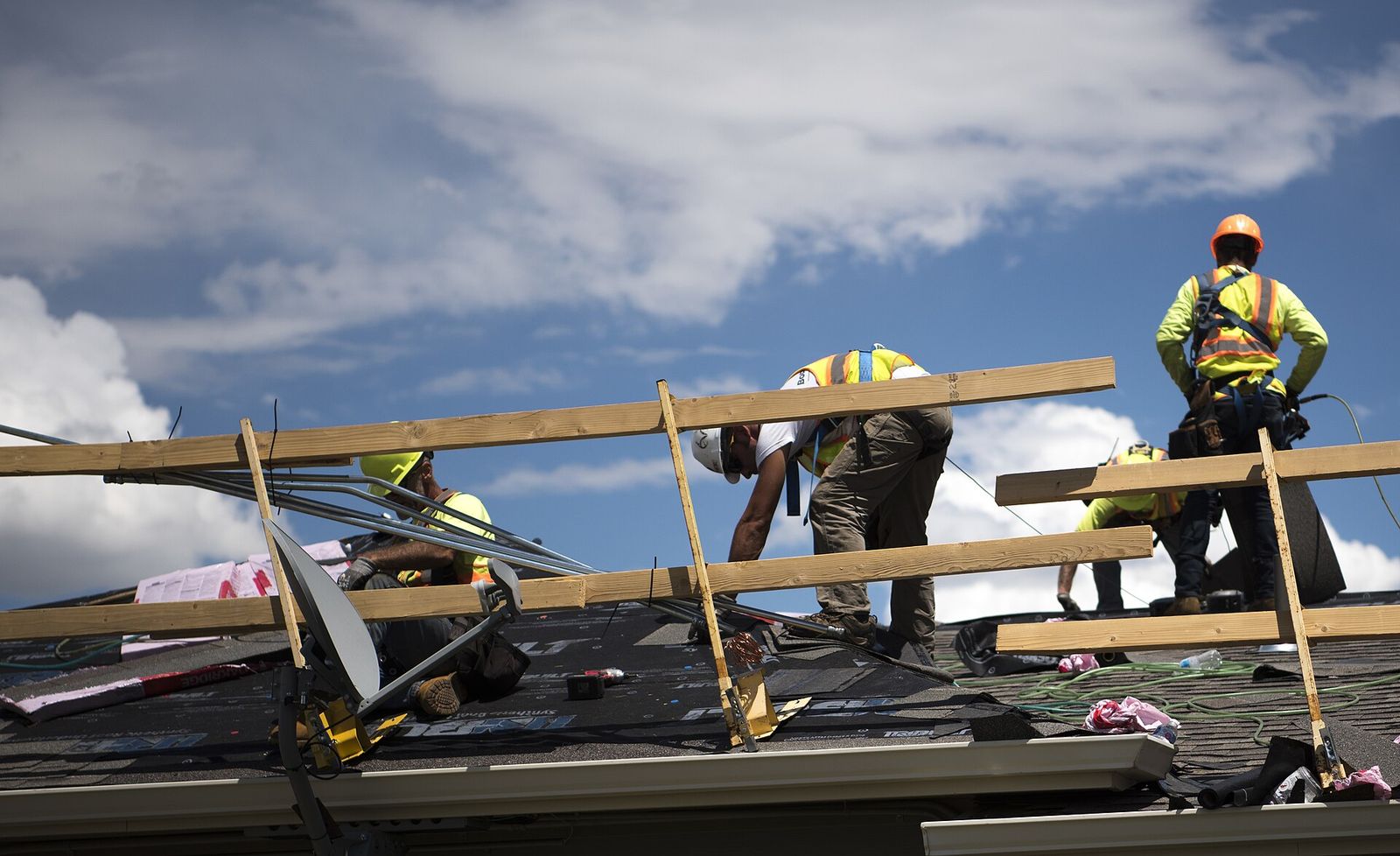 Roofing crew working a shingle roof under a cloudy sky