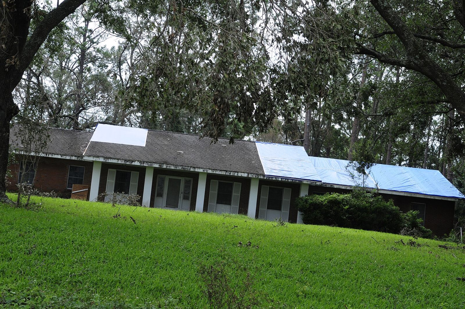 Ranch house with a tarp over part of the roof after a storm