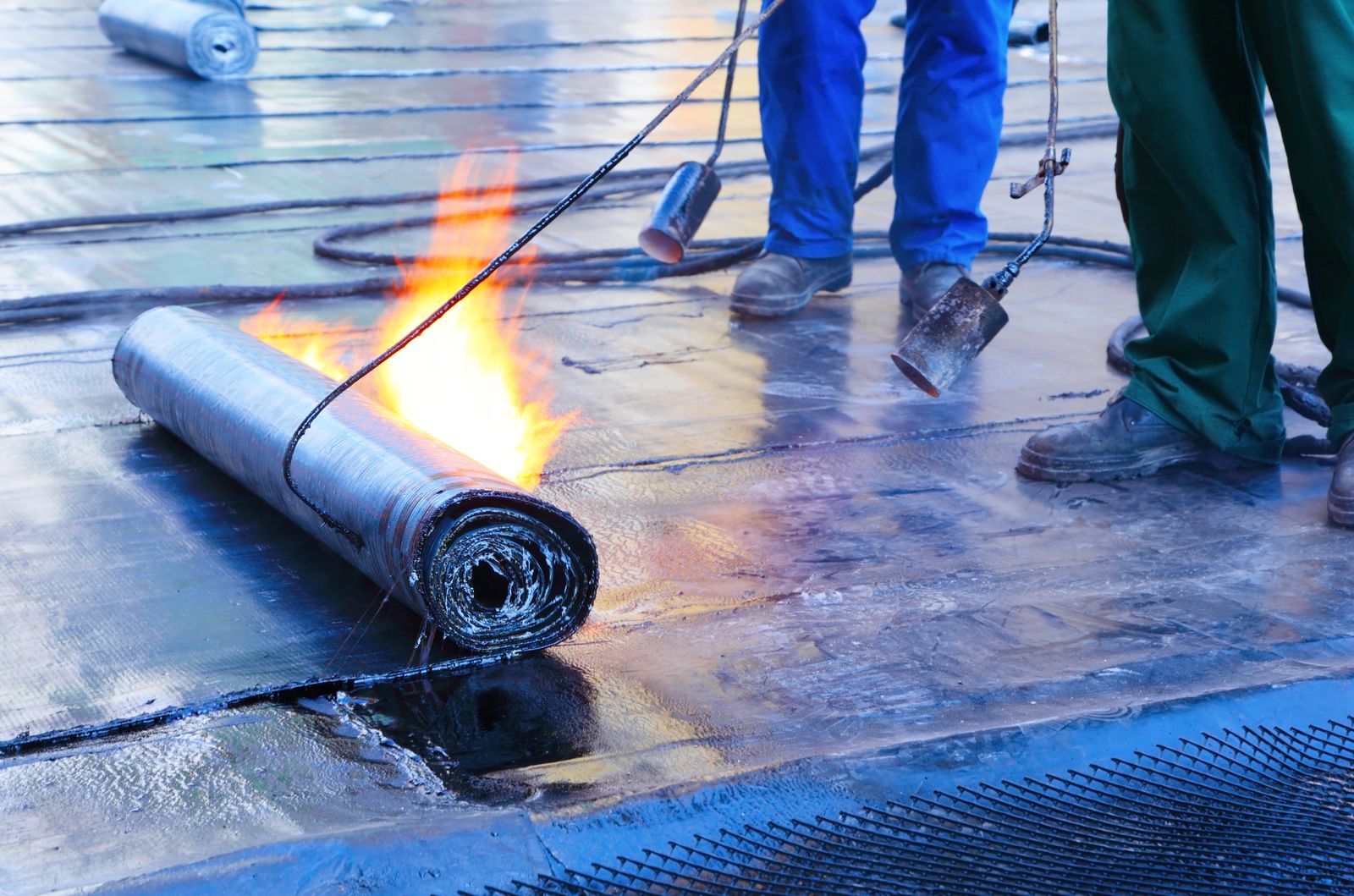 Roofer torching modified bitumen on a flat commercial roof
